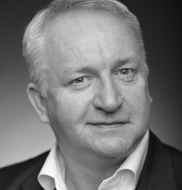 Black and white headshot of a middle-aged man with a neutral expression, showcasing leadership training.